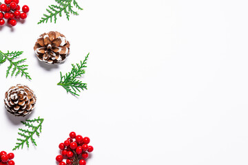 Wall Mural - Minimalism style Christmas composition with fir tree twigs, pine cones and bright red berries on white background top view. 