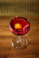 Wall Mural - A red cocktail in a nick and nora glass garnished with an orange zest