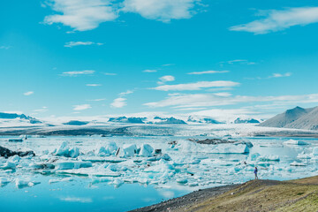 Wall Mural - iceland famous travel destination. jokulsarlon glacier landscape with woman hiker looking at view of