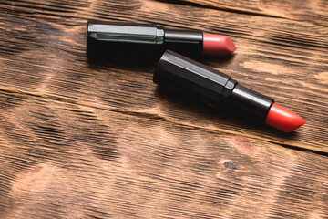 Two lipstick on the brown wooden table background with copy space.