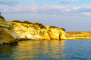 Rocky coast covered with greenery on the beach.