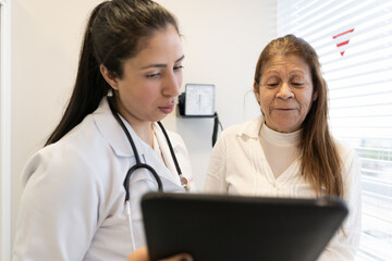 Young brazilian female physician with tablet explaining medical procedures in doctors office health, medical, medicine concept..