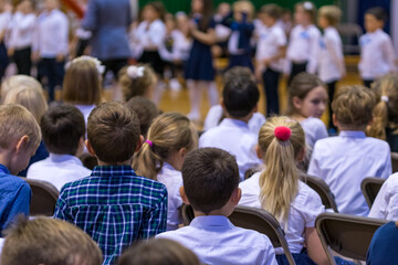 Legionowo, Poland - October 25, 2019: Start of the school year. Students, parents and teachers in the gym during school celebrations. Children in formal clothes, white shirts and dark pants.