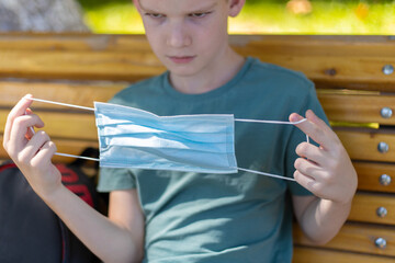 Young caucasian boy looking at the medicine mask then wearing it