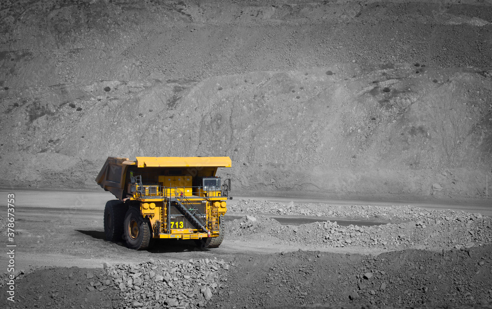 Spot color large yellow truck used in a modern coal mine in Queensland, Australia. A truck transports coal from open cast mine. Fossil fuel industry, Climate change, Environmental challenge. No logos
