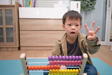 Cute asian kindergarten using the abacus with beads to learn how