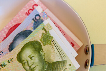 Chinese renminbi notes in a frying pan.