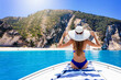 © moofushi - Attractive, blonde woman in bikini sits on a boat and enjoys the excursion to the famous Myrtos Beach of Kefalonia island, Ionian Sea, Greece