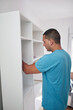 © astrosystem - Man assembling furniture in new apartment, moving in and being hardworking.
