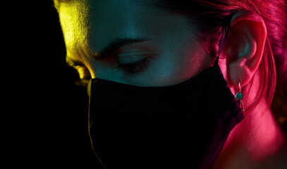 Poster - health, safety and pandemic concept - close up of sad young woman wearing reusable protective mask over black background