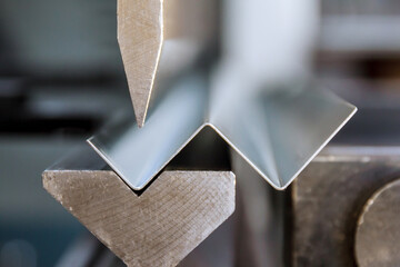 Bending of galvanized sheet metal on a hydraulic bending machine at the factory.