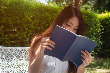 Women hands holding the book to reading in the garden at cafe. Relaxation and reading concept. Weekend activity concept.