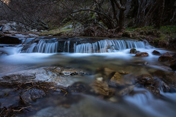 Wall Mural - River water flows among the rocks and forms small waterfalls, Rascafría, Madrid, Spain