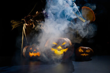 Witch casts a spell on a steaming pumpkin in the dark on Halloween