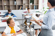 © LIGHTFIELD STUDIOS - selective focus of teacher holding book near multicultural pupils in classroom