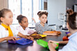 © LIGHTFIELD STUDIOS - selective focus of multicultural pupils sitting in school canteen near lunch boxes