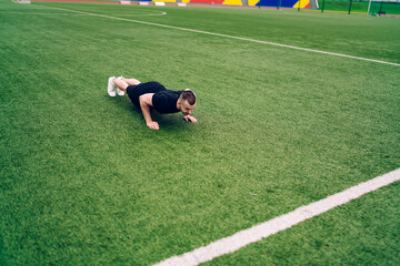 Strong caucasian male athlete doing push ups having workout for warming up muscles,determined 20s hipster guy reaching fitness goals exercising on stadium training body and physical strength