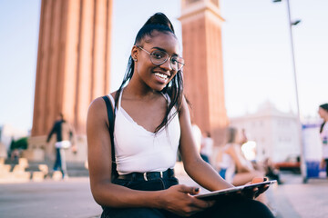 Delighted young ethnic female tourist in city street