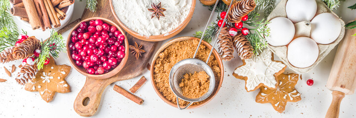 Wall Mural - Ingredients for Christmas cooking, winter baking cookies, gingerbread, fruitcake, seasonal drinks. Cranberries, dried oranges, cinnamon, spices, flour on white table, copy space top view