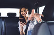 Happy young lady with smartphone giving direction to car driver