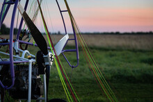 Closeup Of A Motorized Paragliding Trolley With A No-spin Engine, Propeller And Colorful Lines On The Takeoff Field On A Beautiful Evening. Extreme Sports. Paragliding And Small Aircraft.