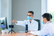 © visoot - Group of doctor wearing protective surgical mask discuss work together and looking at online presentation on computer at hospital.