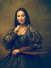 Smoking. Young Woman As Mona Lisa, La Gioconda Isolated On Dark Green Background. Retro Style, Comparison Of Eras Concept. Beautiful Female Model Like Classic Historical Character, Old-fashioned.