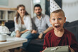 © cherryandbees - portrait of happy young boy holding birthday gift at home, parents in blurred background