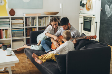 Wall Mural - young family playing guitar with their son at home