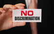 No discrimination words on a card in businessman hand. Social concept against racial and gender discrimination at work