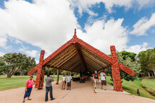 Tourists In Front Of Carved Boathouse With Maori War Canoes