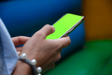 Smartphone with green chromakey on the screen in the hands of a woman. A woman uses mobile app on smartphone with a green screen of chromakey.