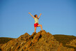 © Natalia Tarasova - a teenage girl in red shorts and a light green T-shirt stands on a rock and experiences vivid emotions from conquering her first height