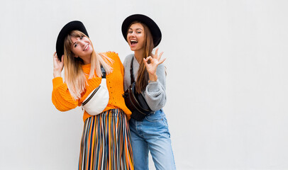 Outdoor photo of two cheerful female friends spending great time together , posing on white background. Autumn concept. Space for text.