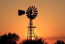 Windmill At Sunset With A Colorful Sky And Tree's North Of Hutchinson Kansas USA Out In The Country.