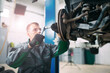© davit85 - Car lifted in automobile service for fixing, worker repairs the wheel,