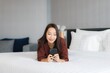 © siraphol - Portrait beautiful young asian woman use smart mobile phone on bed