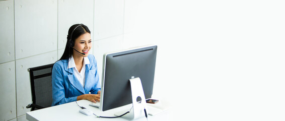 Attractive business woman Asian in suits and headsets are smiling while working with computer at office. Customer service assistant working in office