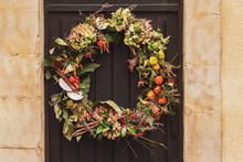 Wreath With The Red Berries And Dry Leaves Hanging On A Door.