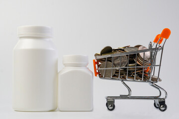 Coin in a mini shopping cart and pill bottles on white background.