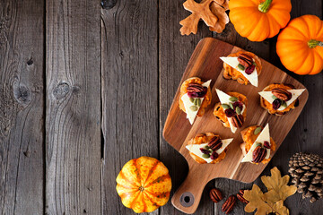 Wall Mural - Autumn crostini appetizers with pumpkin spread, cheese and nuts. Above view table scene on a rustic wood background with copy space.