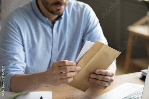 Fotomural Crop close up of man sit at desk open envelope with paper letter or correspondence at office