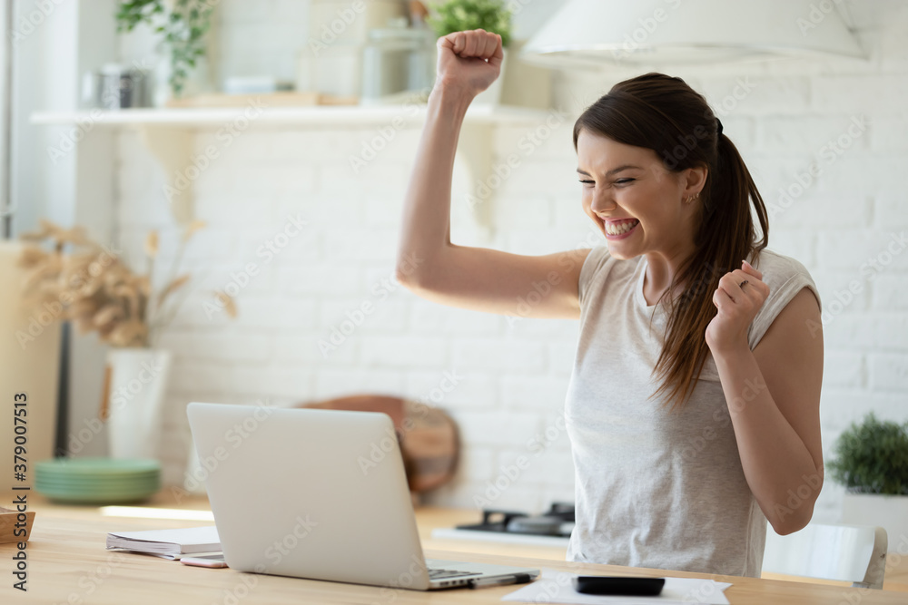 Woman with laptop and calculator excited about finally paying down her mortgage. Young lady super happy about refund approval email. Smiling millennial woman celebrating successful online investment - obrazy, fototapety, plakaty 
