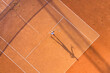Healthy lifectyle. A young girl plays tennis on the court. The view from the air on the tennis player. Dirt court. Sport background. Aerial view from drone.