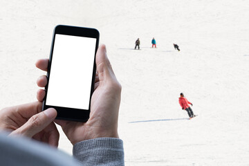 Mockup of man using mobile smart phone with people skies in winter as background