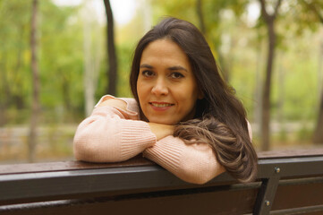 Portrait of a woman sitting on a bench in the park.