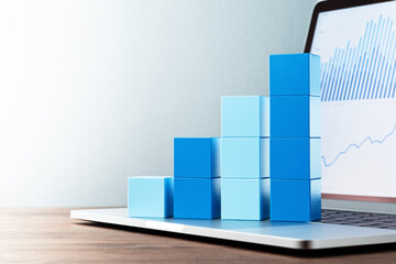 Aufkleber - Laptop and bar graph. Blue graphs on laptop screen. Stacked blue cube and laptop on wood table
