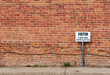 Antique grungy reddish brown brick wall texture background in a common bond brickwork pattern, with a visitor parking sign and copy space