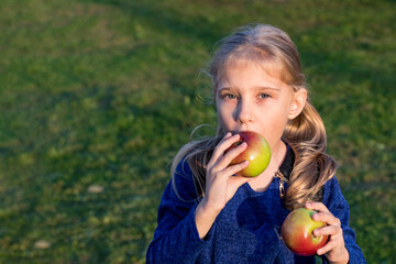 soft focus. Daylight. A girl with white hair holds two red apples in her hands. The sun is low.