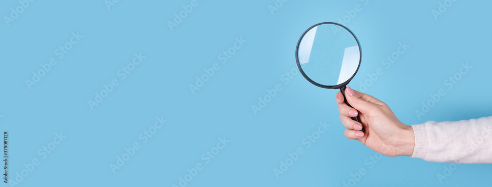 Magnifying glass in hand on a blue background, copy space template, banner. - obrazy, fototapety, plakaty 